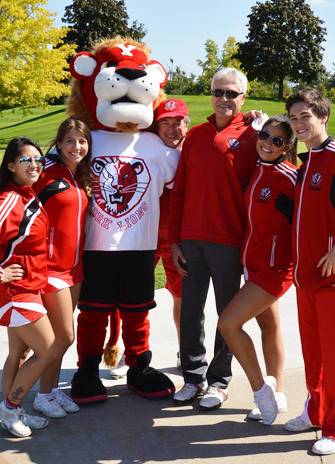 President with cheerleaders and mascot at golf tournament.