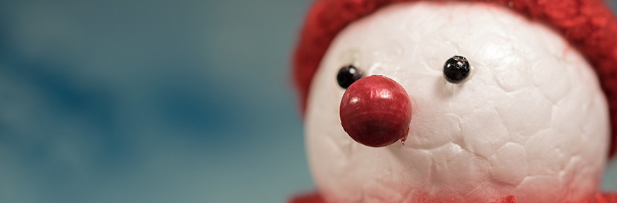 A handcrafted snow man with a red nose and wearing a red knitted cap.