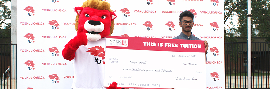 The York Lions mascot presents the first year free tuition prize to Shayan Nandi