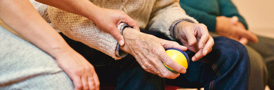 Hands of older adults, one with a ball