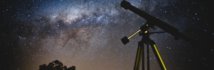 Black telescope under blue and black sky