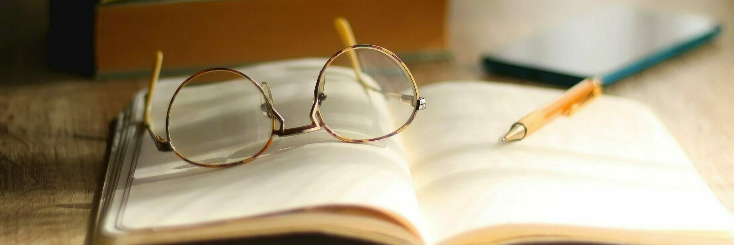 open book with glasses and pen