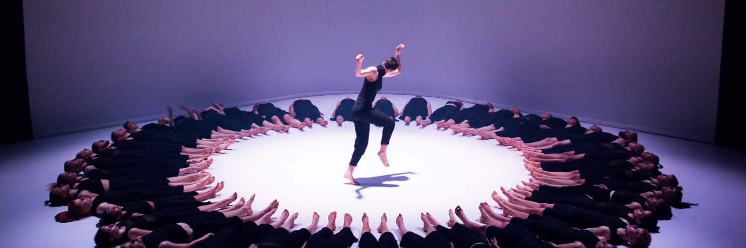 Colossus performers lay on floor in circle around single jumping dancer, photo by Mark Gambino courtesy of TO Live credit Mark Gambin