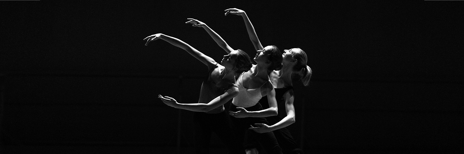 Three dancers posing on dimly lit stage, stock banner from pexels