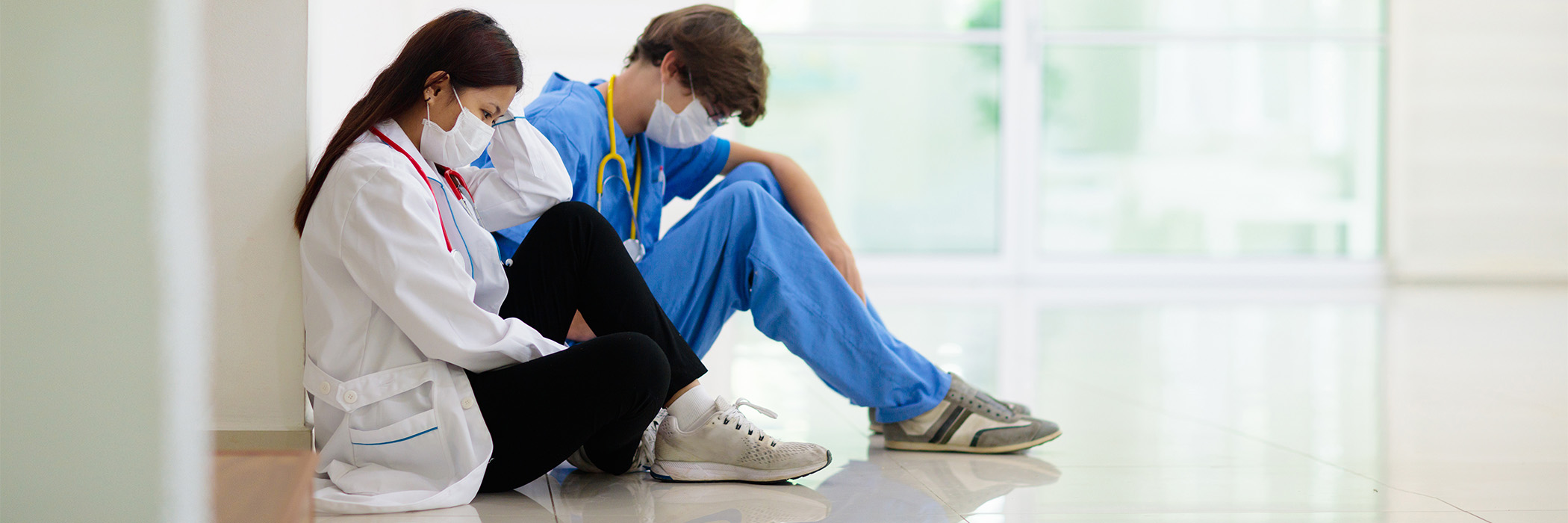 Exhausted nurse, doctor, medical practitioner sitting on care centre floor