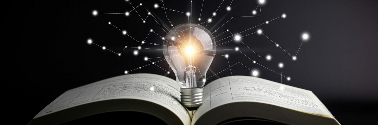 Lightbulb with orbs over an open book
