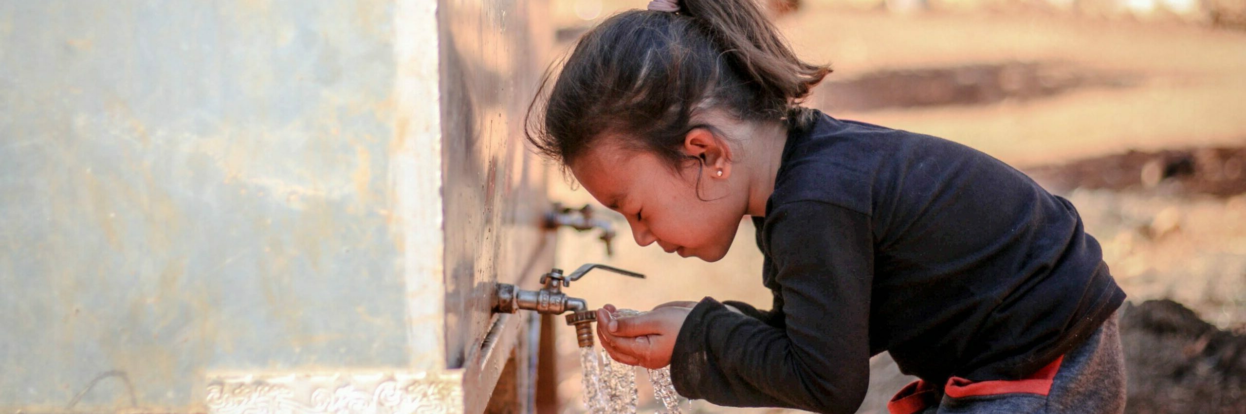 Child drinking water from outdoor tap water well