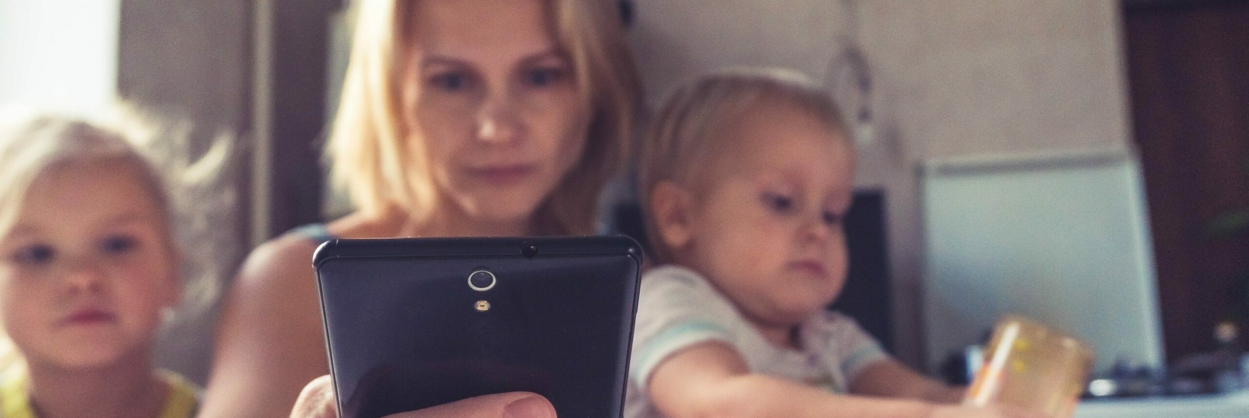Woman with two children, holding smartphone