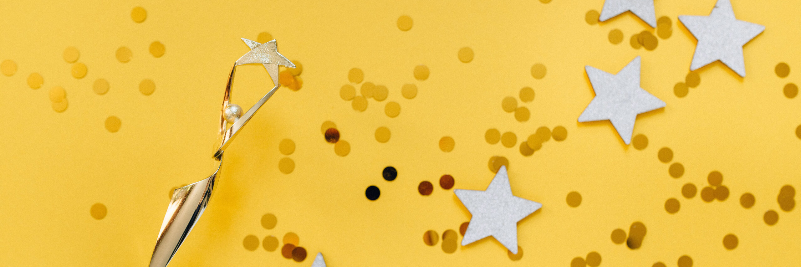 Gold trophy, stars and confetti on a yellow background