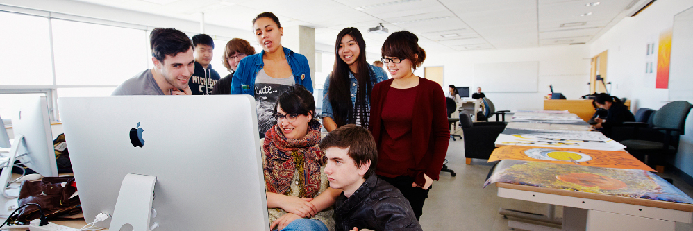 Group of students working at a computer monitor BANNER